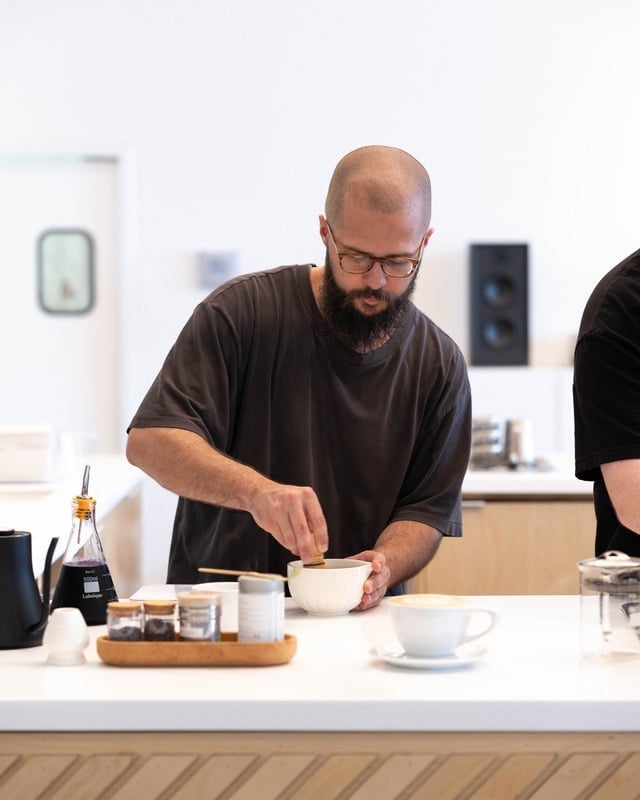 Hand stirring coffee in glass brewing vessel